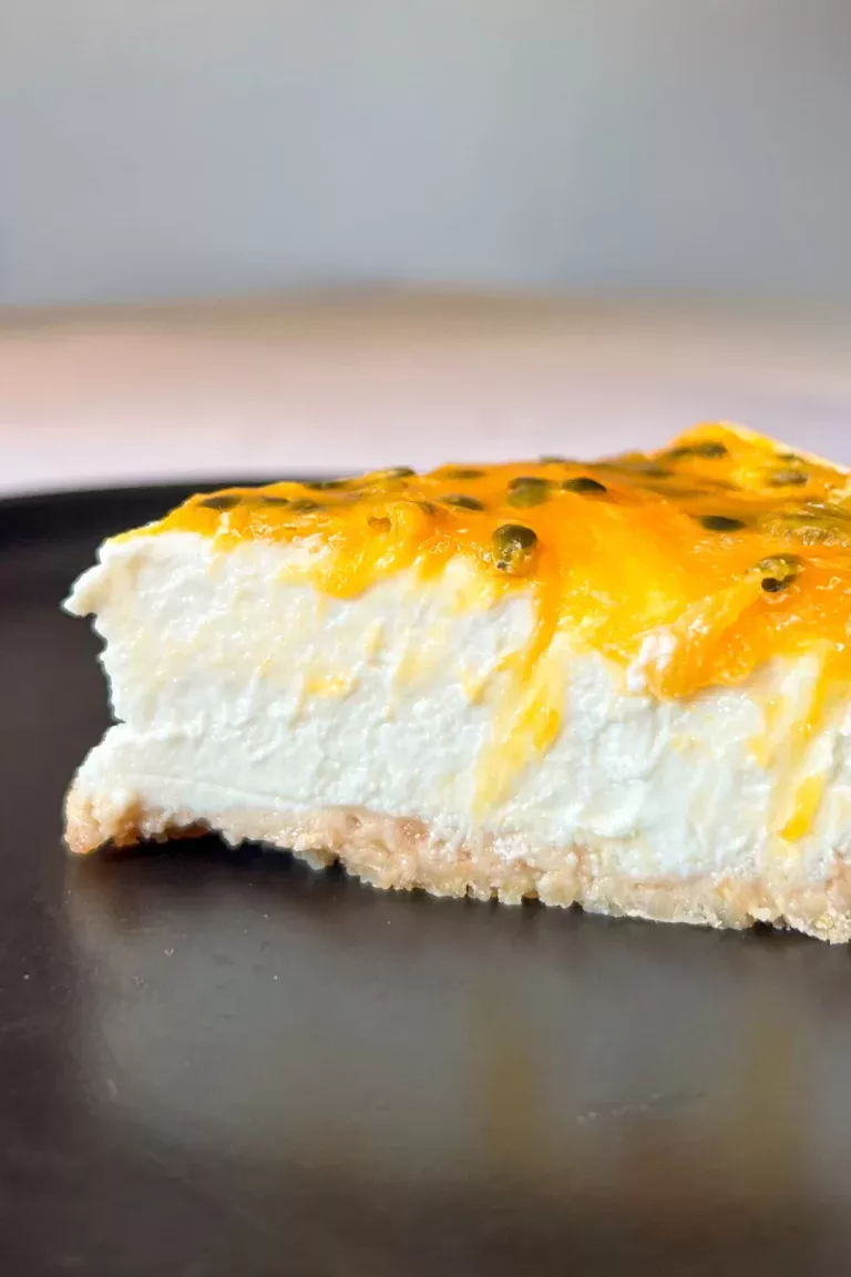 Slice of high-protein cheesecake with passion fruit topping on a thin biscuit base