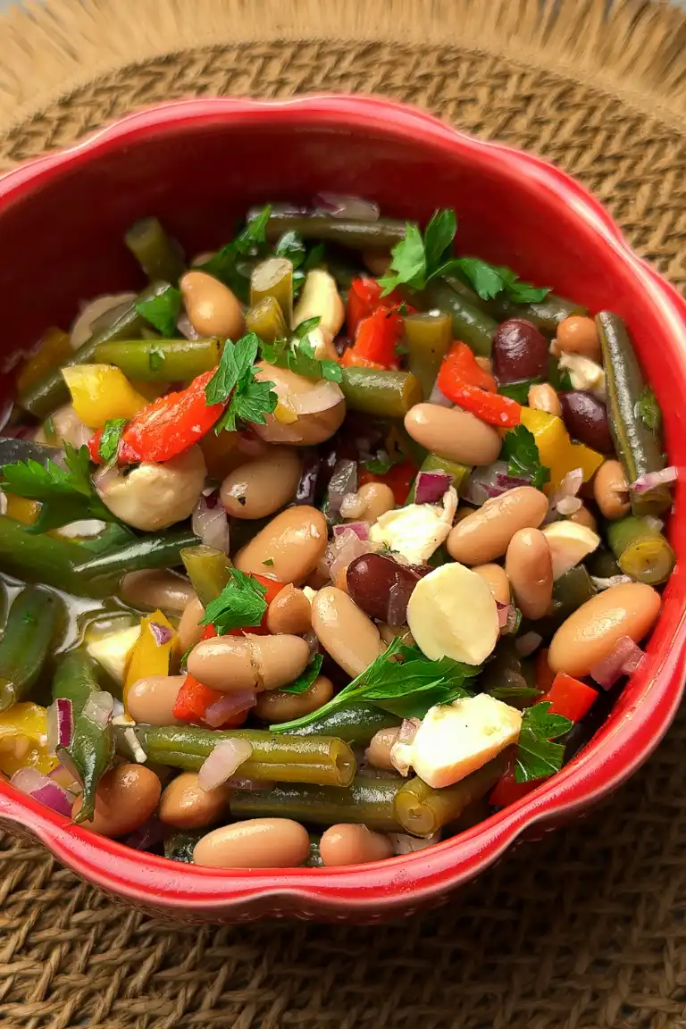 Festive five bean salad with green beans, peppers and mozzarella pearls in a red bowl